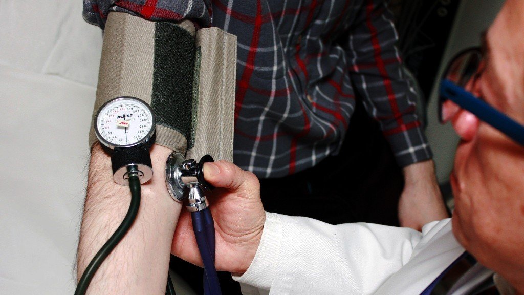 Male doctor checking blood pressure of younger male