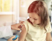 A child receiving a vaccine injection from a doctor in a clinical setting